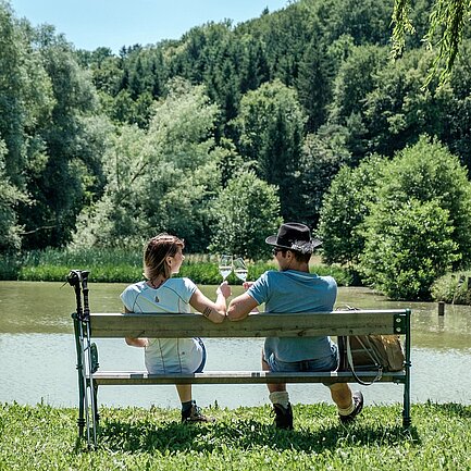 Pärchen sitzt auf einer Bank am See in der Region Loipersdorf