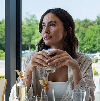 A woman enjoying a cup of coffee at breakfast at Thermenhotel Vier Jahreszeiten.